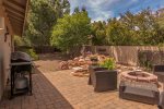 The fenced in backyard has outdoor seating with a BBQ grill and outdoor firepit